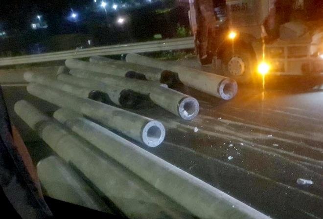 Đứt cáp neo, hàng chục cột điện cao áp trên xe đầu kéo văng xuống đường, gây họa cho xe khách