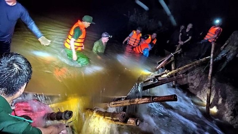 Lực lượng quân đội, công an địa phương dầm mình trong dòng nước siết để vá đê. (Ảnh: Báo Nghệ An).