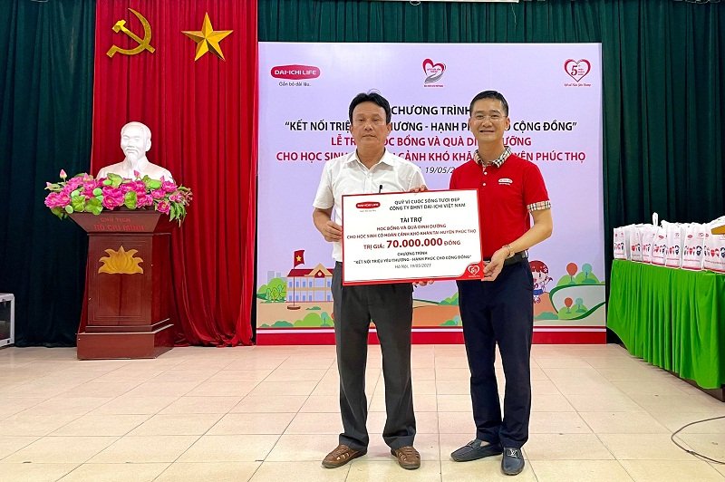 Ông Ngô Việt Phương - Phó Tổng Giám đốc Kinh doanh Kênh Đại lý Ttruyền thống Dai-ichi Life Việt Nam trao tấm séc tượng trưng số tiền trao tặng học bổng và quà dinh dưỡng cho ông Hoàng Văn Lan, Bí thư Đảng ủy xã Phụng Thượng, huyện Phúc Thọ