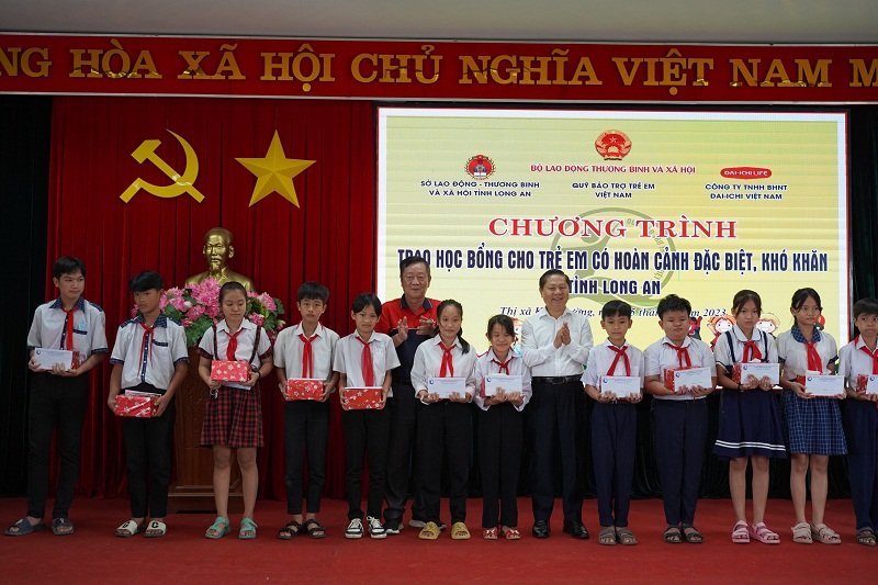 Ông Lê Tấn Dũng – Thứ trưởng Bộ Lao động - Thương binh và Xã hội (áo trắng) và ông Phùng Đắc Lộc – Giám đốc Đối ngoại kiêm Giám đốc Quỹ Vì cuộc sống tươi đẹp trao học bổng cho các em học sinh.