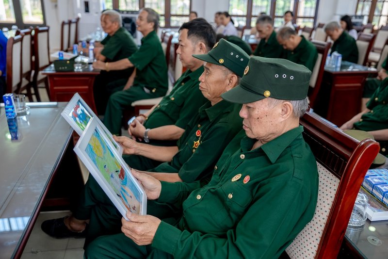 Các bác cựu chiến binh chăm chú đọc những dòng chữ nhỏ, được các em gửi kèm trong mỗi bức tranh (Ảnh: Duy Cường). 