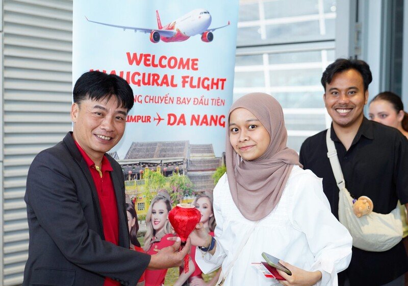 Đại diện Vietjet - Giám đốc VP Miền Trung Vietjet - ông Trần Hoàng Linh chào đón và tặng quà hành khách trên chuyến bay khai trương