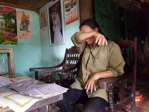 Bà Trần Thị Lục, mẹ của Huy khóc nức nở bên cạnh tập giấy khen học sinh giỏi của con trai