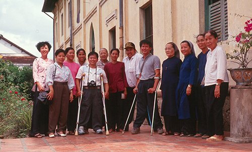 Nguyễn Quốc Túy (áo trắng, đội mũ) đứng cạnh mẹ Nguyễn Thị Bé (áo đỏ) cùng những người bạn và các xơ tại cô nhi viện ở Sa Đéc năm 1993. Ảnh: Nhân vật cung cấp
