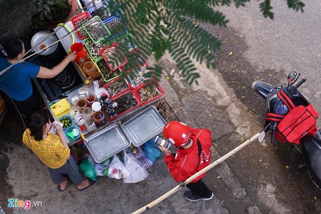 Một shipper đang thực hiện đơn hàng tại một quán ăn ven đường. Ảnh: Việt Đức.