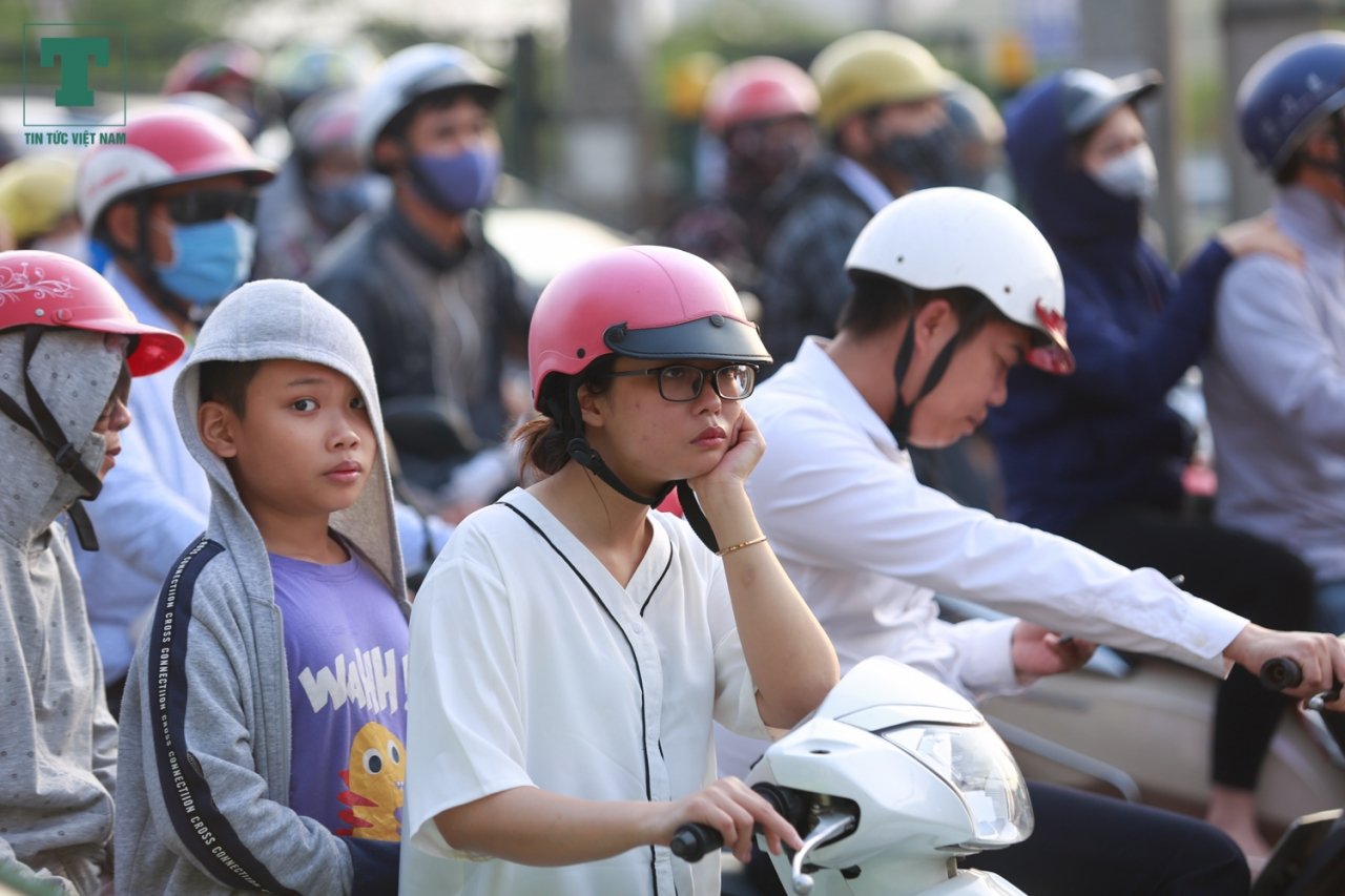 Một người phụ nữ mệt mỏi đứng chờ để di chuyển giữa dòng người đông đúc.