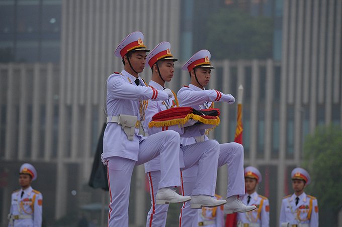 Ba chiến sĩ thực hiện nghi thức trang trọng tại chân cột cờ. Nghi lễ treo băng tang được tiến hành song song với nghi thức chào cờ thường ngày.
