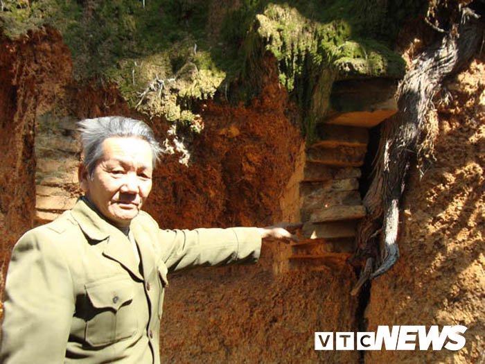 Ông Trần Văn Ngoang bên một ngôi mộ Hán lộ ra từ vách núi.