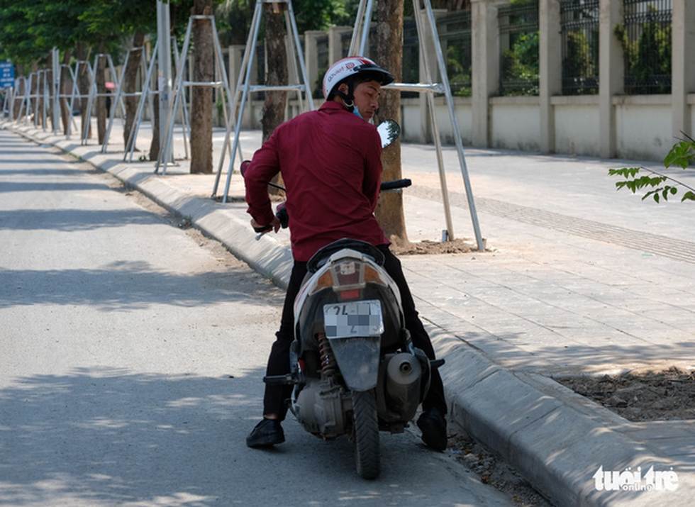 Người đi đường lánh tạm vào những bóng cây để tránh cái nóng - Ảnh: NAM TRẦN