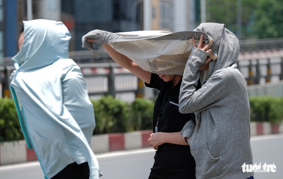 Người dân ăn mặc và che chắn kín để đi ăn trưa dưới thời tiết nắng nóng - Ảnh: NAM TRẦN