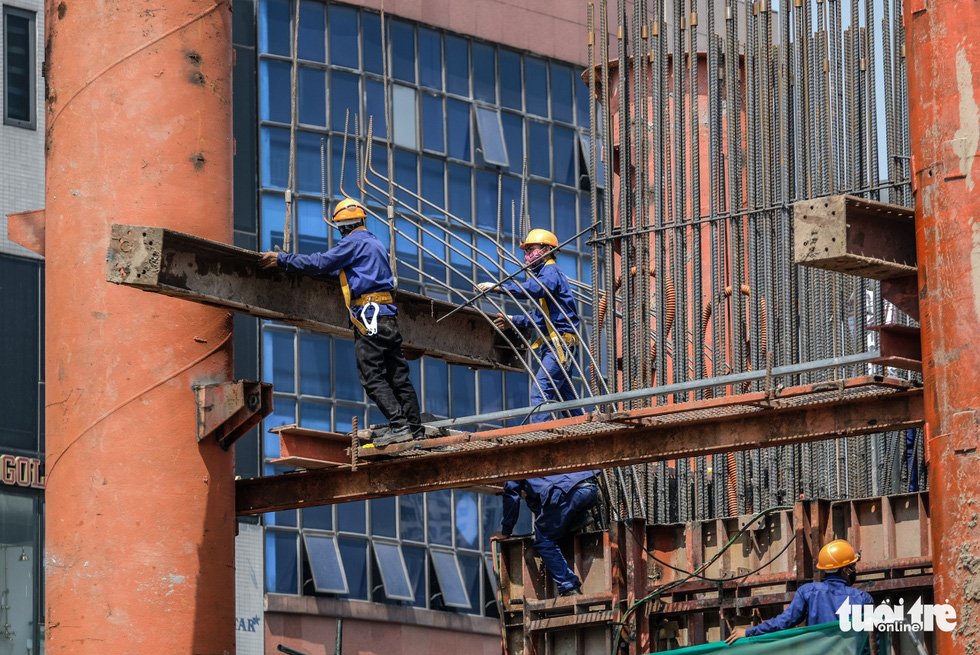 Công nhân bịt kín mít lao động trên công trường vành đai 2, đường Trường Chinh dưới cái nắng gắt buổi trưa - Ảnh: NAM TRẦN