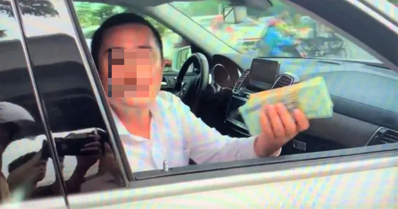 Hình ảnh người đàn ông giơ bọc tiền cố thủ trong xe Mercedes khi bị CSGT TP HCM kiểm tra.