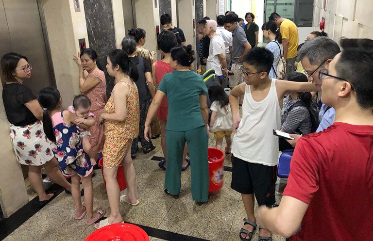 Người dân ở Linh Đàm khổ sở bê từng xô nước sau vụ nước sạch có mùi khét. (Ảnh: IT).