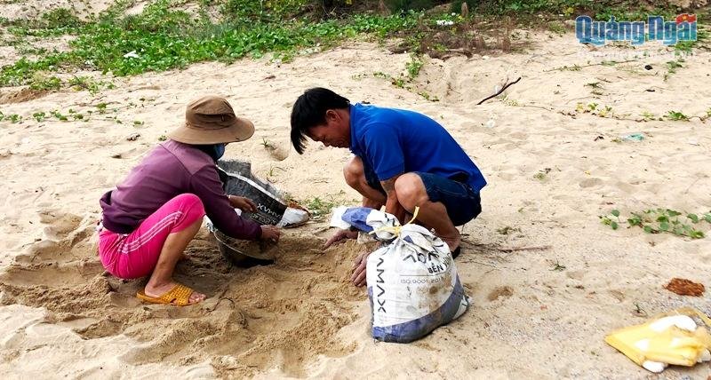 Người dân Quảng Ngãi xúc cát che chắn nhà. (Ảnh: Báo Quảng Ngãi).