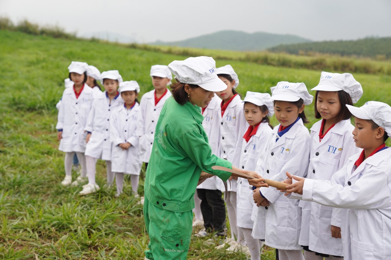 Cô Vinh (áo xanh), chia sẻ với các em nhỏ về kỹ thuật chăm sóc và nguồn gốc thức ăn cho bò organic)