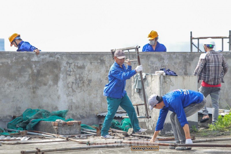 Hàng chục công nhân với đầy đủ đồ bảo hộ đang tiến hành các công việc tháo dỡ phần sai phạm. (Ảnh: NĐH).