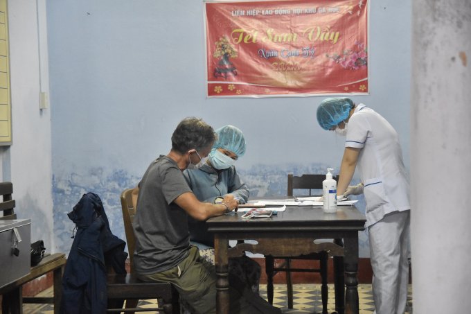 Một du khách nước ngoài được giải thích về việc kiểm tra y tế và hướng dẫn điền thông tin sức khỏe, lịch sử đi lại...