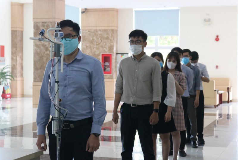 Cán bộ công nhân viên đo thân nhiệt với máy đo thân nhiệt tự động trước khi vào làm việc.