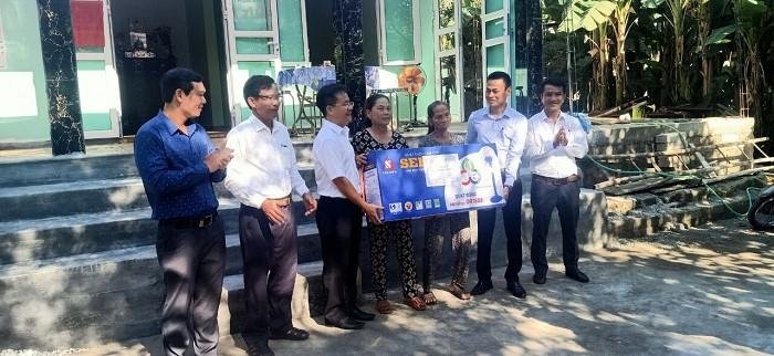 Đại diện PC Điện lực Thừa Thiên Huế tặng quà chúc mừng gia đình có ngôi nhà mới khang trang hơn.
