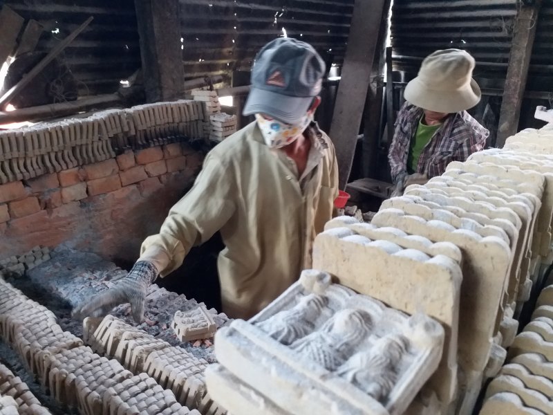 Vợ chồng ông Võ Văn Nam, có hơn 30 năm làm nghề nặn ông Táo, cẩn thận xếp tượng vào lò nung.