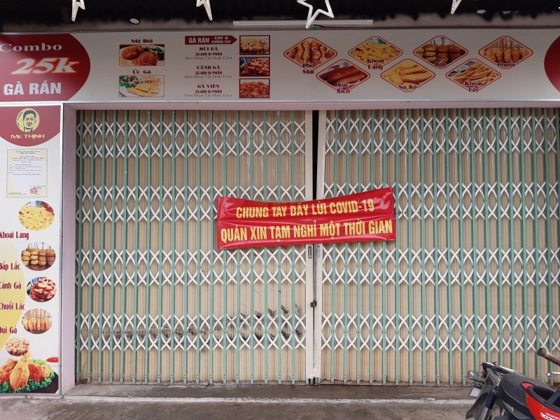 “Chung tay đẩy lùi COVID-19 quán xin tạm nghỉ một thời gian”. Băng rôn treo trước cửa một quán bán gà rán, khoai lang lắc...