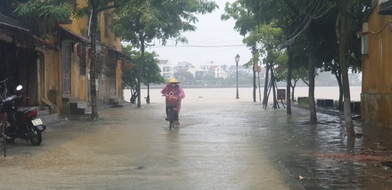 Người dân đạp xe trên con đường ngập nước.