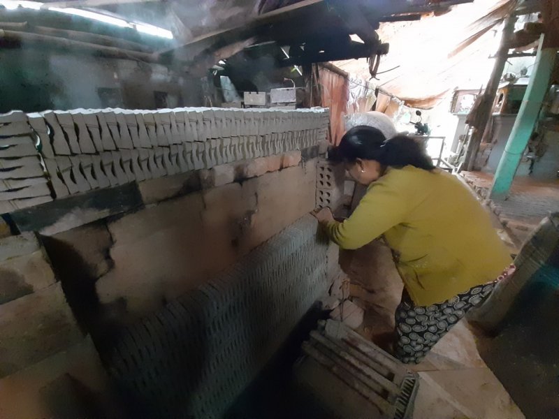 Tranh thủ sức nóng của lò, vợ ông Nhật sấy tượng khi trời mưa