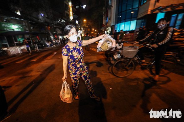 Một người dân mừng rỡ cầm các túi rác ra vứt vào thùng rác phía ngoài khu vực cách ly. Ảnh: Tuổi trẻ.
