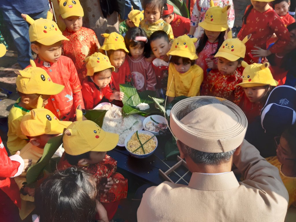 Các em nhỏ chăm chú học cách gói bánh chưng.