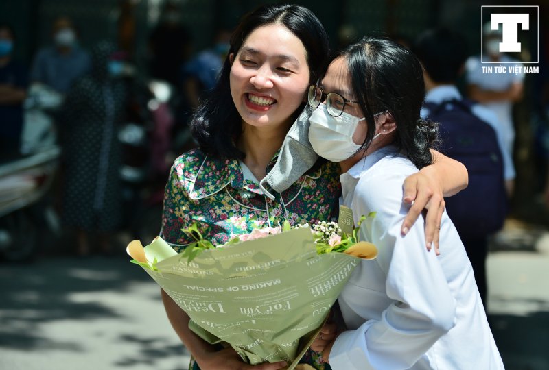 Cảm xúc từ bất ngờ đến vỡ òa của thí sinh khi được cô giáo tặng hoa chúc mừng lúc bước ra cổng trường.