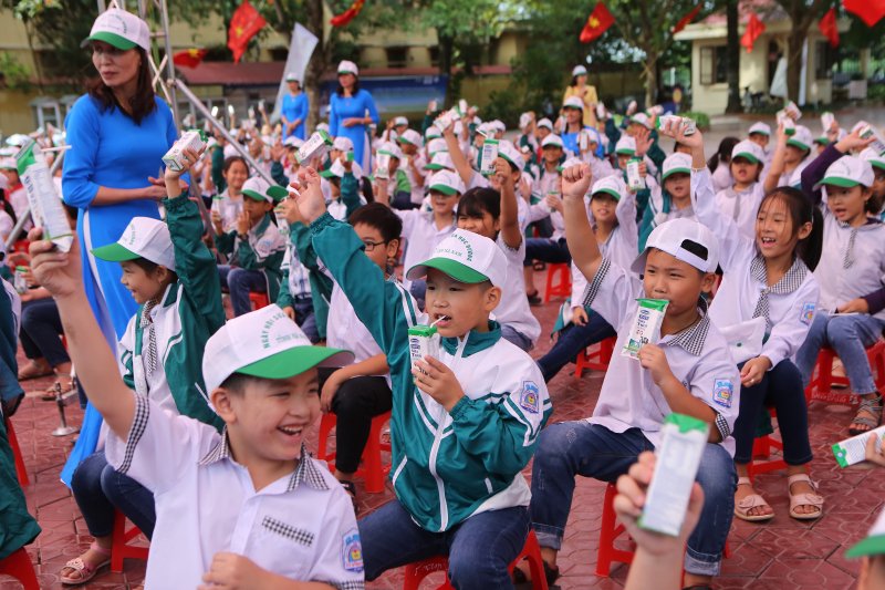 Các em học sinh Trường Tiểu học A hào hứng tham gia hoạt động uống sữa cùng các bạn tại sân trường trong buổi lễ phát động